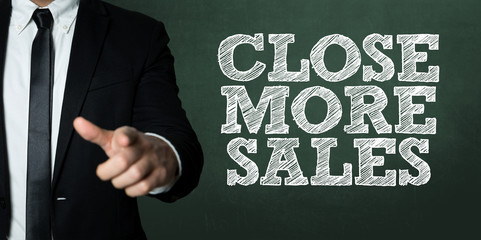 Business man pointing with the text: Close More Sales