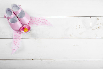 Fondo de madera blanca con artículos de bebé en rosa mostrando el concepto de espera o embarazo de una niña