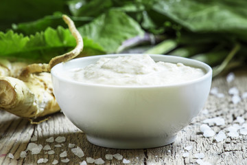 Ground horseradish, hot sauce to the food in a white bowl, roots