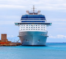 A blue and white luxury cruise ship tied up to a pier under nice sky