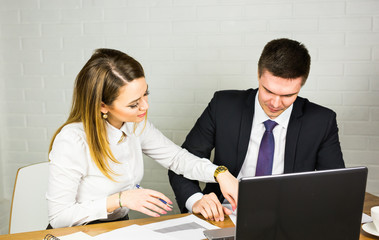 Obraz premium Two entrepreneurs sitting together working in an office desk comparing documents.
