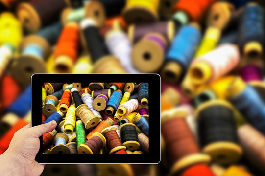 Tablet photography concept. Taking pictures on a tablet. Colored high contrasted threads for sewing