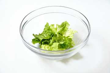 Green salad and arugula in transparent bowl isolated on white