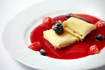 Delicious pancakes with berry sauce on plate isolated on white