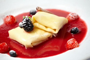 Delicious pancakes with berry sauce on plate isolated on white