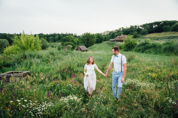 Naklejka na ściany i meble Happy Bride and groom walking on the green grass