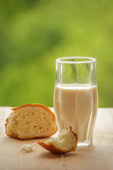 A glass of milk on wooden . Slices of white bread. Green background