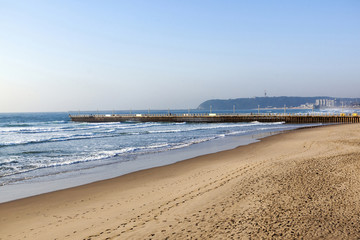 Empty Beach Sea and Concrete Pier Against Blue Sky