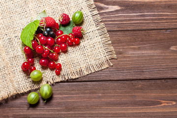 A mixture of ripe berries on a wooden table. Berries on a napkin, top view, empty space for text. Beautiful summer background