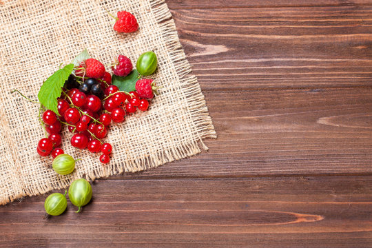 A mixture of ripe berries on a wooden table. Berries on a napkin, top view, empty space for text. Beautiful summer background