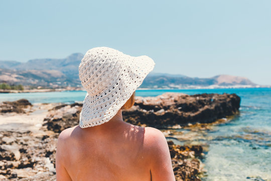 woman with straw hat protects from sun on the beach