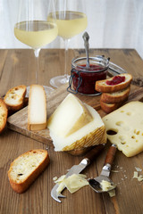 Different types of cheeses on a table with toast and cranberry jam