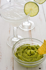 Margarita cocktail, guacamole and nachos on a white wooden table

