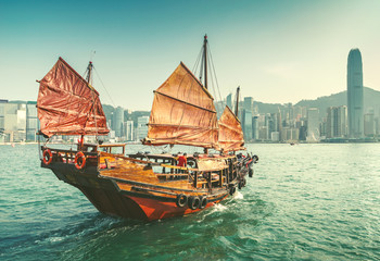 Scenic view over Hong-kong skyscprapers and a junkboat sailing. Iconic landmark of Hong-Kong.