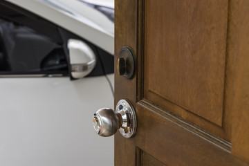 silver knob on wood door house open to a white car