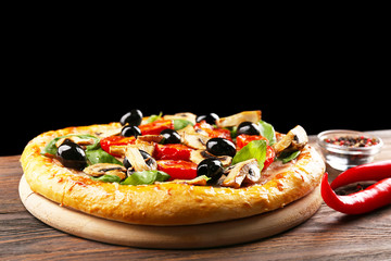 Delicious tasty pizza with ingredients on wooden table