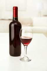 Glass of red wine with bottle on blurred interior background