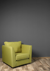 Green armchair on dark grey wall background