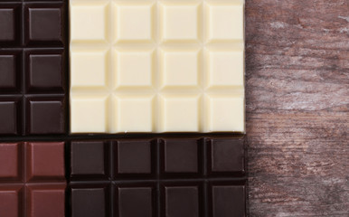 Different chocolate bars on wooden background