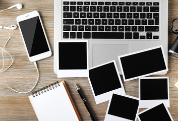 Laptop, phone, photos on a wooden desk background, top view