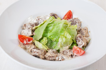 salad with meat in a creamy sauce, ase, lettuce, romaine, iceberg cherry tomatoes on top of the plate isolated