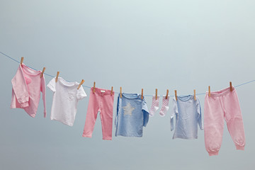 Baby clothes hanging on rope on grey background