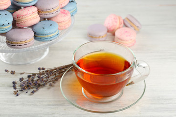 Tasty macaroons with tea on wooden table