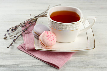 Tasty macaroons with tea on wooden table