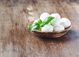 Mozzarella cheese with basil in wooden rustic bowl. selective focus.