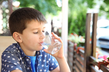 Cute boy drinking water in cafe