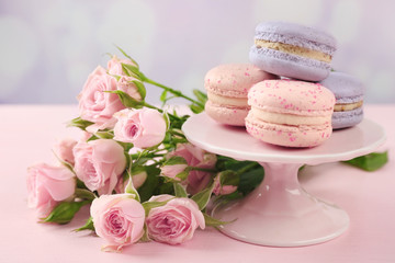 Obraz na płótnie Canvas Tasty macaroons with beautiful roses on pink background
