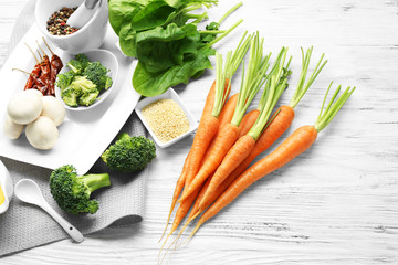 Carrots with vegetables and spices on wooden table