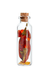 Dried whole chili peppers in glass bottle on white background