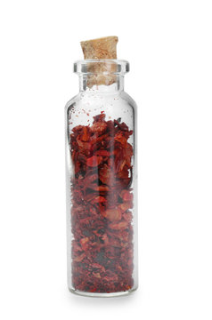 Dried chopped chili pepper in glass bottle on white background