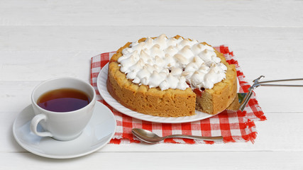 Sweet cake decorated with meringue and cup of tea