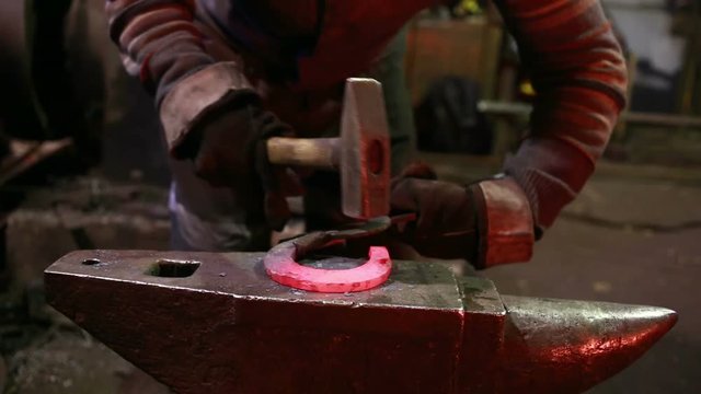 The smith in a smithy forges a horseshoe