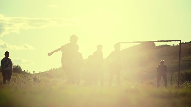 Village boys is playing football in the sunshine day. Slow motion.
