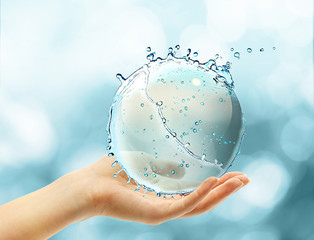 Female hand holding abstract water ball splash on blur bokeh background