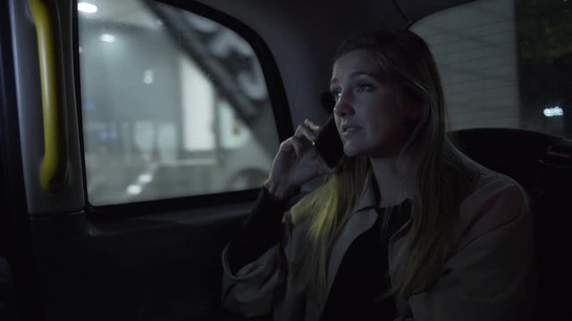 Young adult female in taxi using smart phone