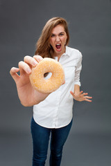 hysterical beautiful young woman screaming against a fat donut
