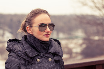 Portrait of young beautiful woman early spring in the park in a black scarf and jacket