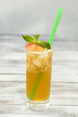 Fresh apple juice in a glass with straw on wood background