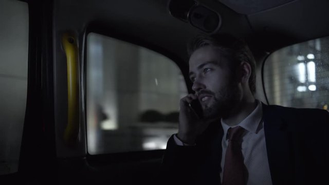 Young adult business male in taxi using smart phone