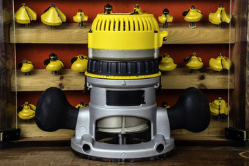 electric power router in front of wood cabinet full of assorted yellow metal router bits