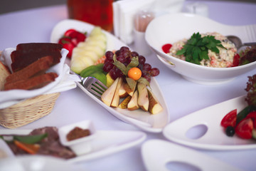 Beautifully decorated catering banquet table with different food snacks and appetizers with sandwich, caviar, fresh fruits on corporate christmas birthday kids party event or wedding celebration