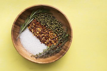 Wood dish and condiments on yellow background