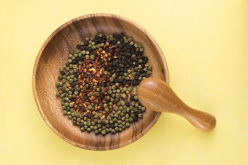 Wood spoon and pepper on yellow background