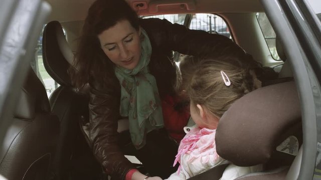 Girl playing harmonica and mother fastening girl's seat belt