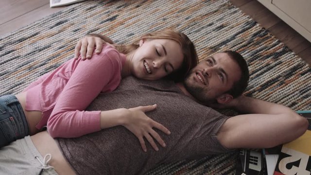 Young couple lying on rug and discussing  smiling