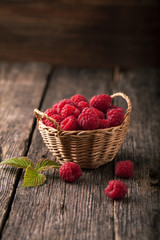 Ripe fresh raspberries with leaves in a basket